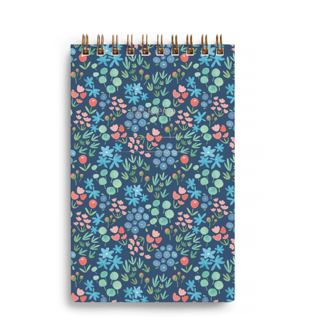 Cover of the task pad covered by a meadow of flowers, mostly blues, greens, and light orange, with wire-o binding at the top.