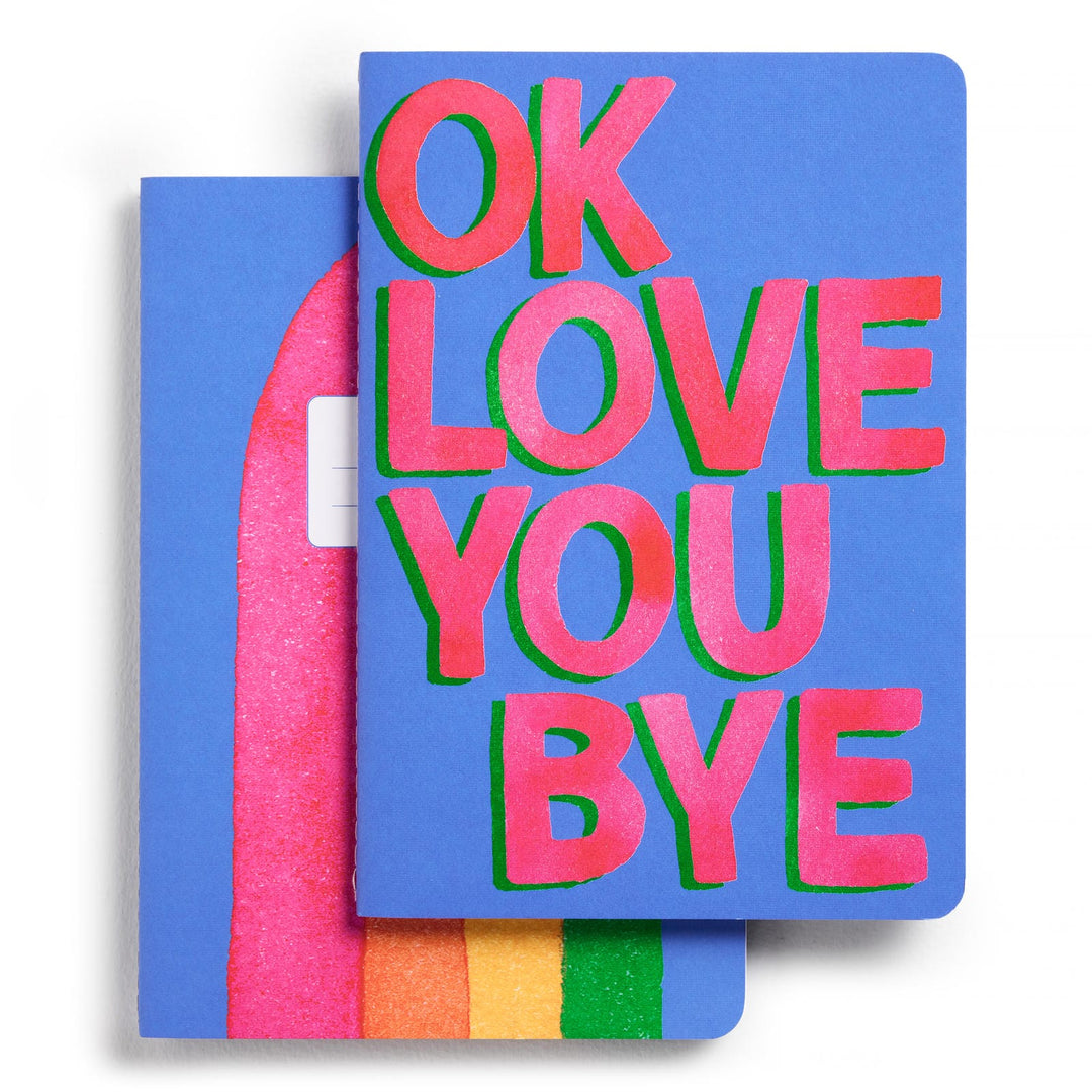 Two blue notebooks, one with 'OK LOVE YOU BYE' in large red and pink letters, the other a large rainbow.