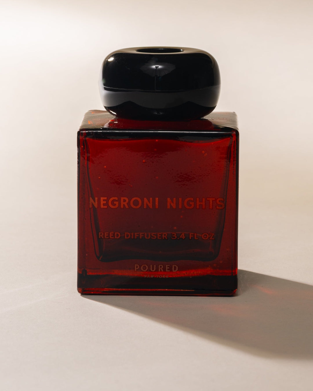 Red bottle labeled 'Negroni Nights' and "REED DIFFUSER 3.4 FL OZ' with a black lid.