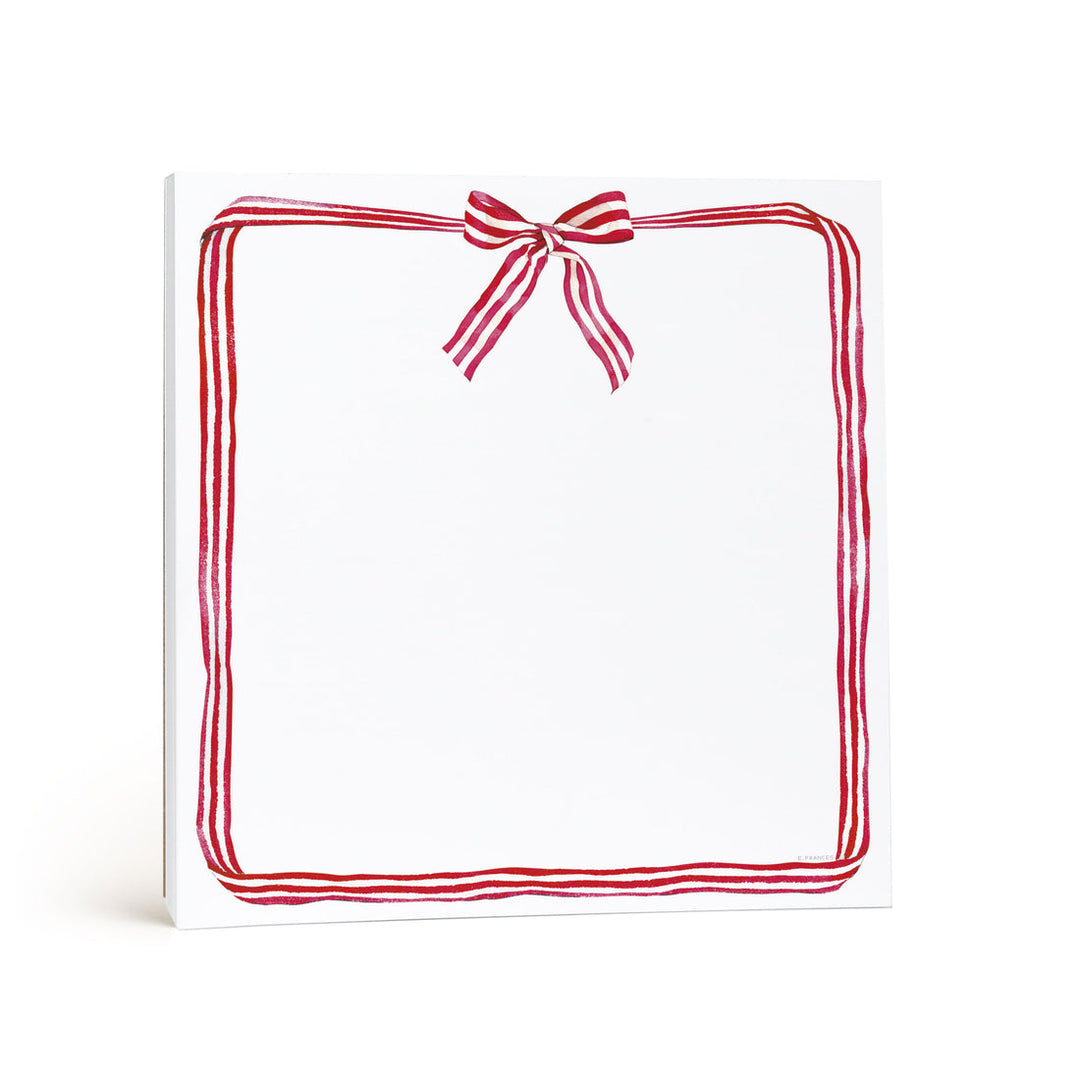 White notepad with ribbon candy surrounding the page, tied with a bow at the top.