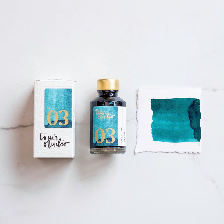 The box of Tom's Studio 03 Neptune Ink next to its bottle and a paint swatch.