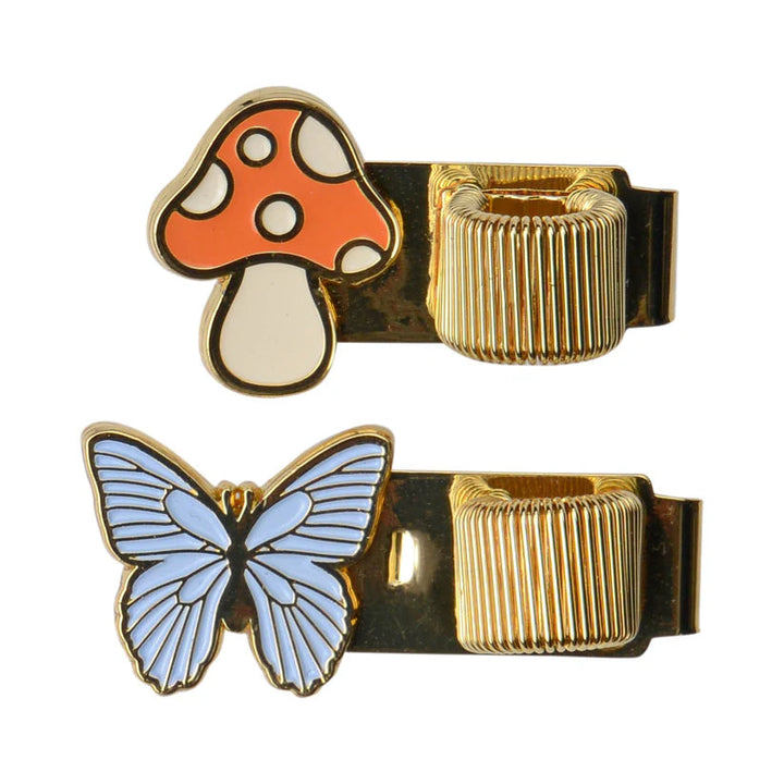 Two clips, one a mushroom in off-white and orange next to a gold loop for the pen, over a blue butterfly next to its pen loop.