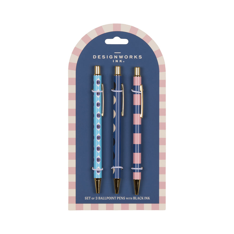 Three pens - one with navy blue dots on light blue, one with white circles on navy blue, and one with blue and pink horizontal stripes - on a blue card with pink and white border.