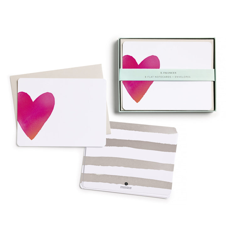 The box of cards, with belly band, next to two stacks of cards, one showing the front, with a large red heart on the left side, and the other the back, with four gray stripes.