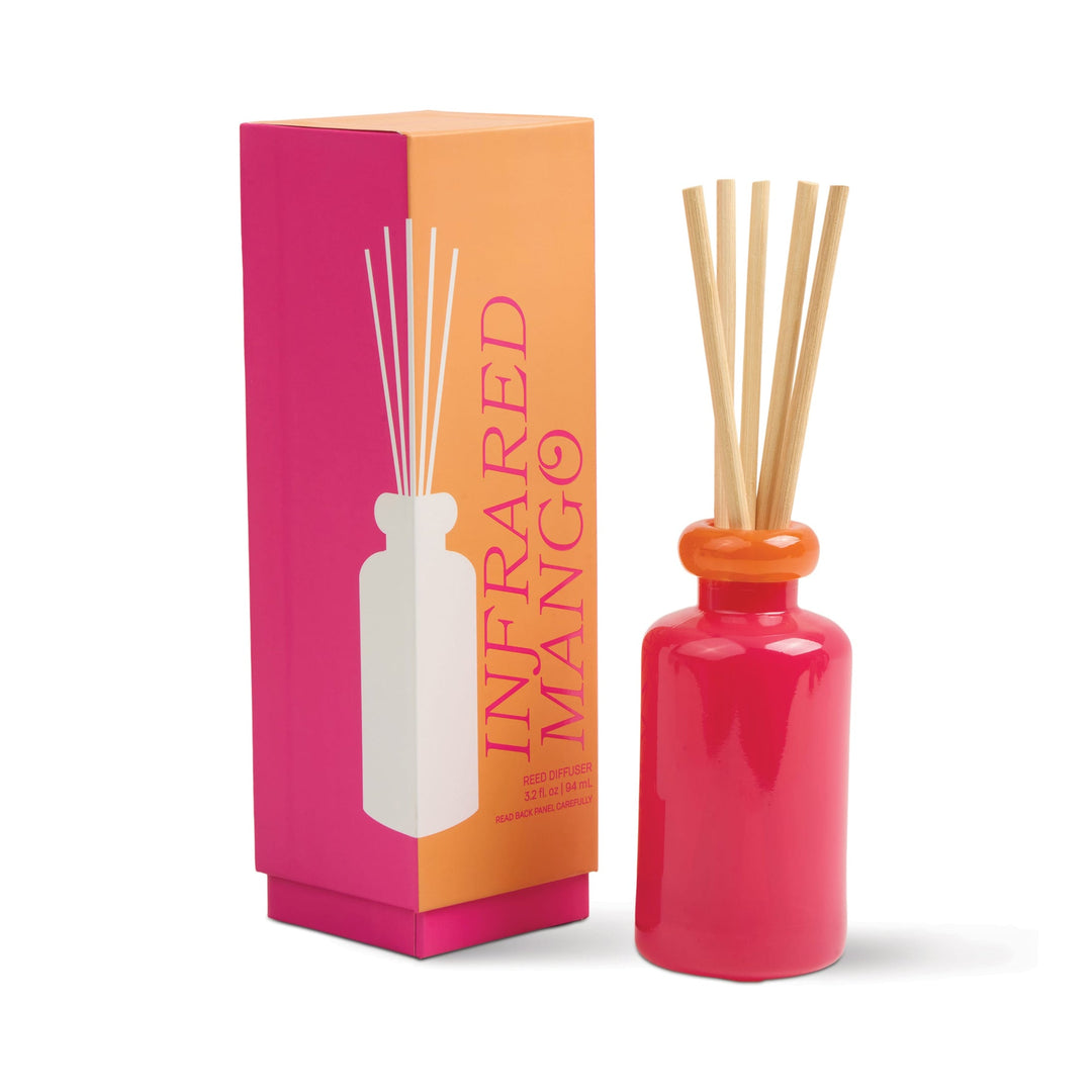 Pink diffuser bottle with orange collar at the top and five wooden sticks next to a matching box.