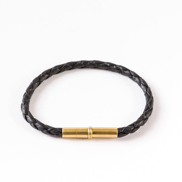 Black braided bracelet with a brass cylindrical magnetic clasp.
