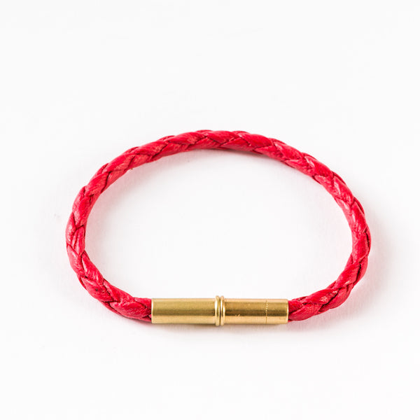 Red braided bracelet with a brass cylindrical magnetic clasp.