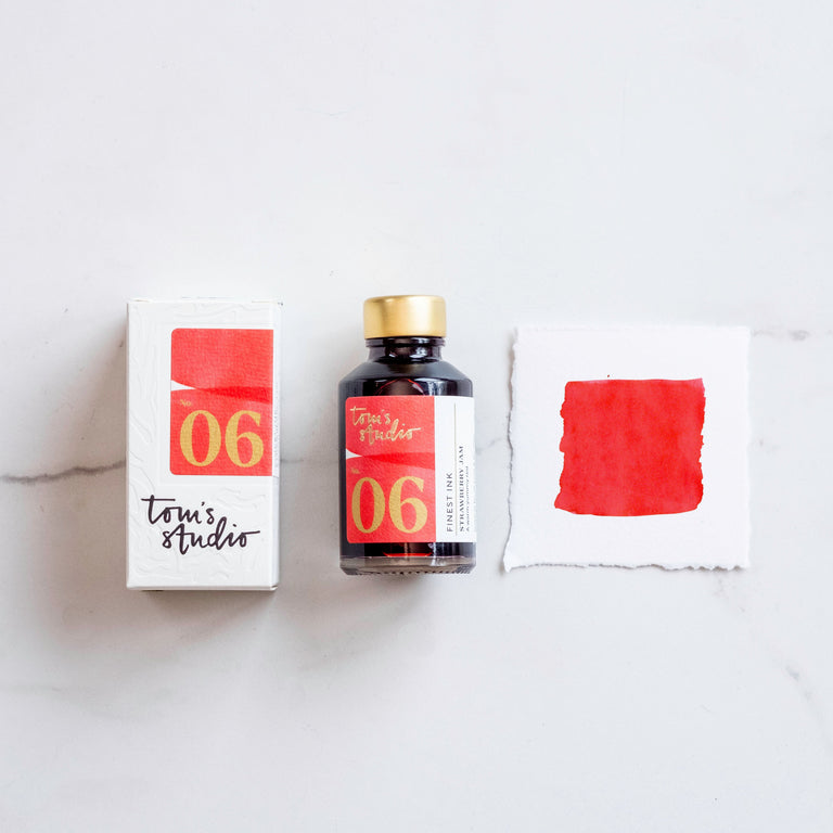 The box of Tom's Studio 06 Strawberry Jam Ink next to its bottle and a paint swatch.