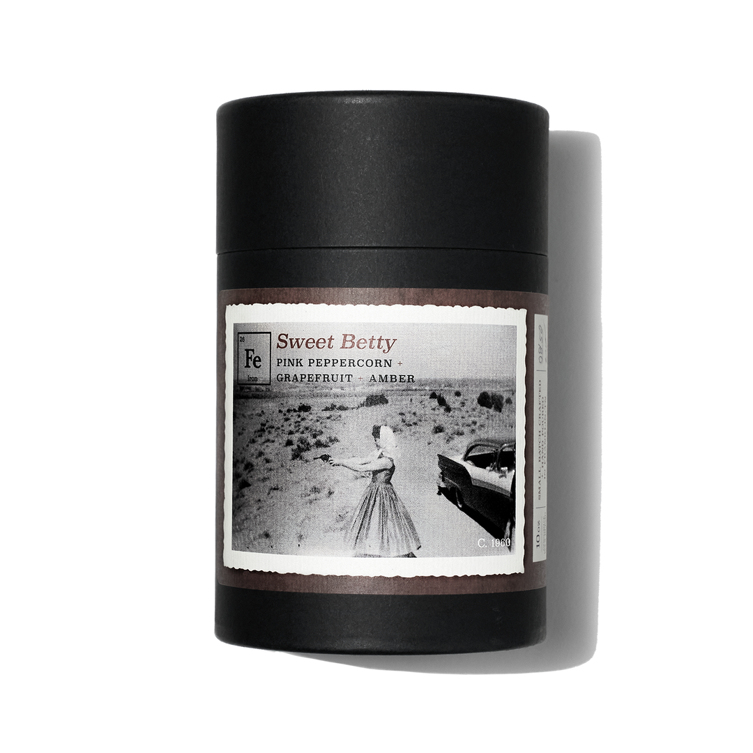 Gift box for Iron Collective candle. Sweet Betty label has a historical image of woman shooting gun in the desert.