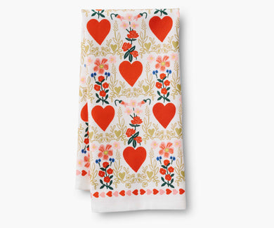Folded tea towel with a pattern of red hearts in a light gold flowery border and small bouquets of red flowers.