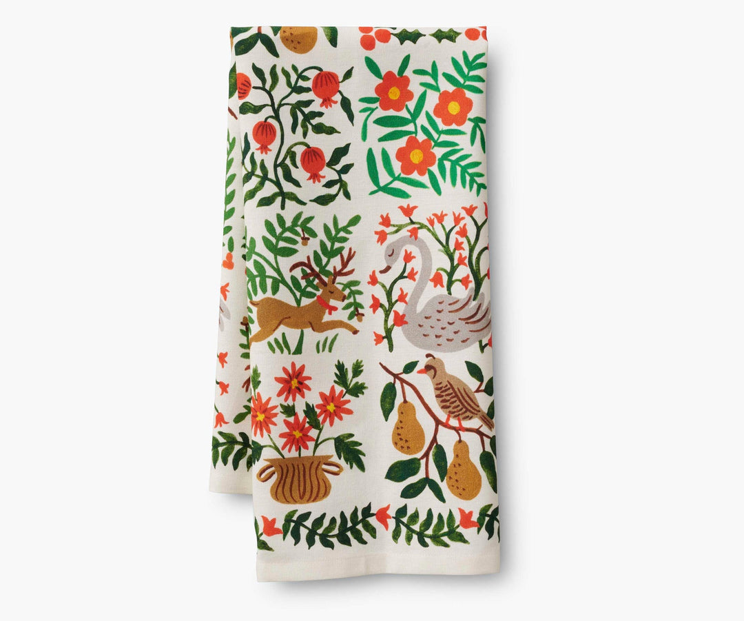 Folded tea towel with floral and nature-themed illustrations of  a swan, deer, partridge in a pear tree, persimmons and flowers.