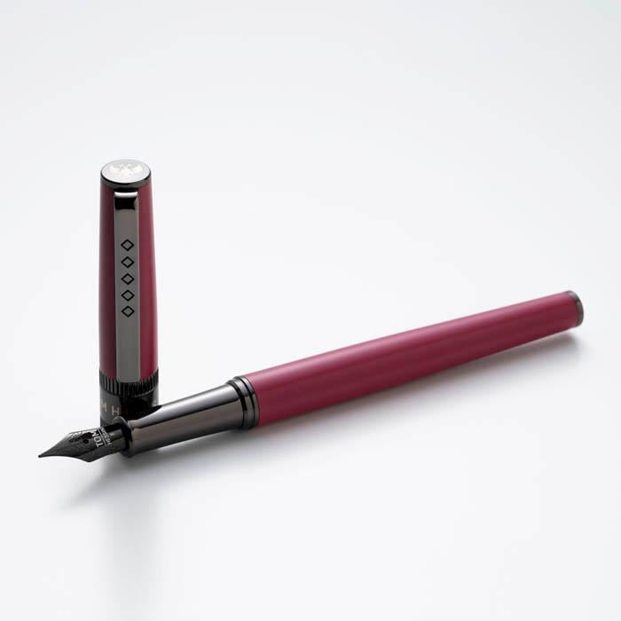 Red lacquered fountain pen next to its upright cap.