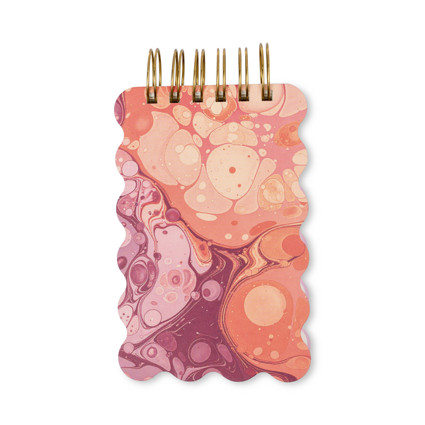 Notebook with pink and orange marbled cover and wavy edges.