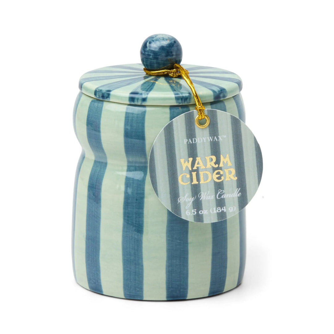 Ceramic candle holder with teal and light green vertical stripes, with a round tag on a gold cord.