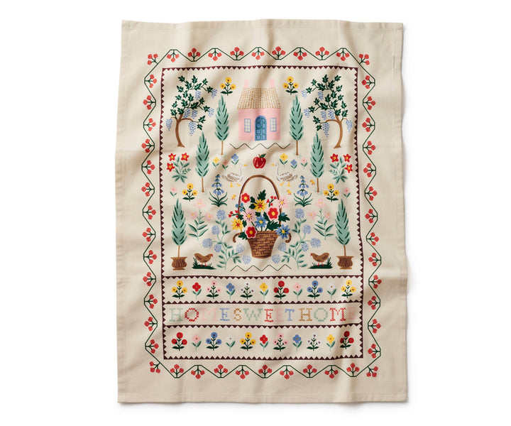 Towel fully open with a red and green border surrounding a garden scene and the text "Home Sweet Home" in cross-stitch pattern.