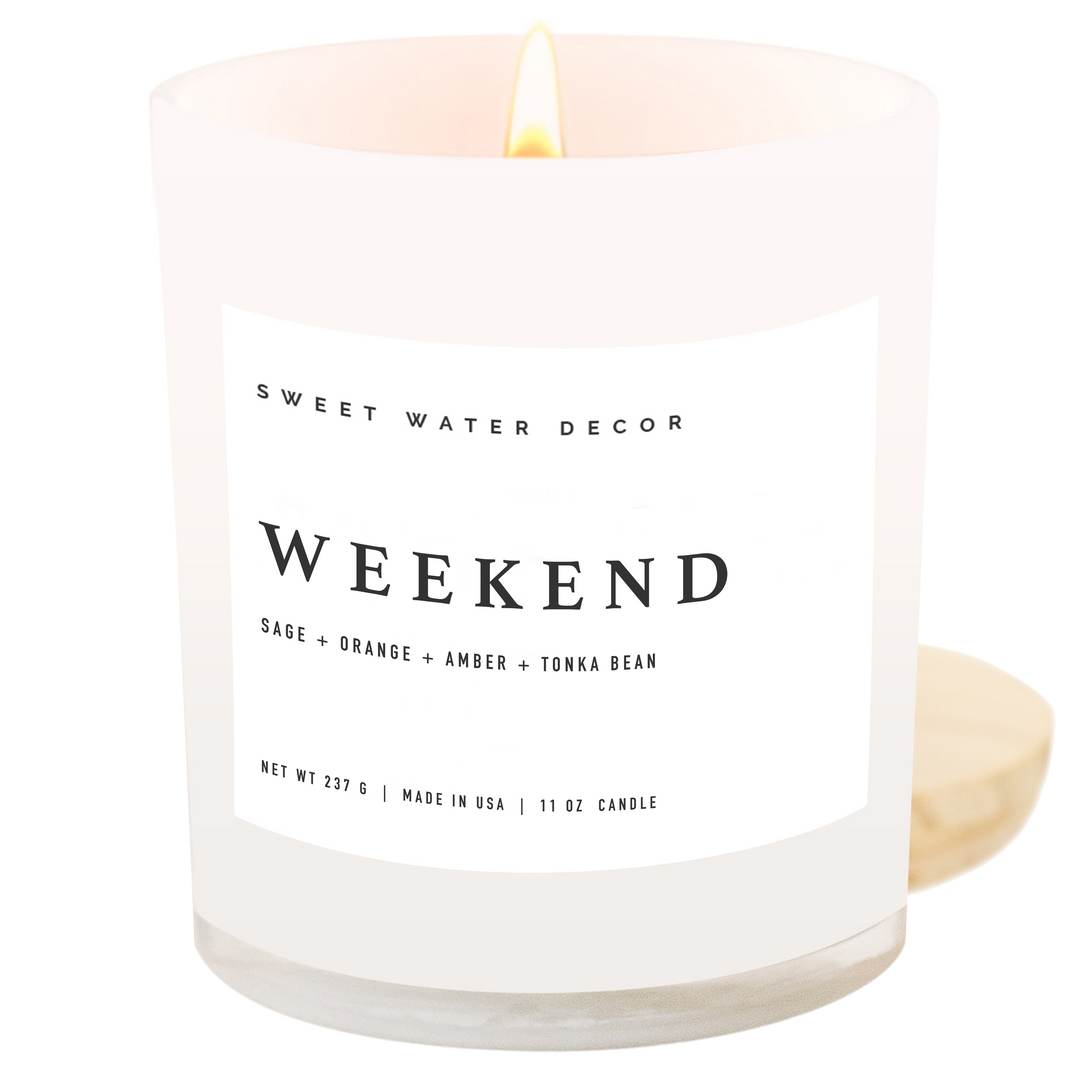 Lit candle in a white opaque jar with wooden lid and black text on a white label.