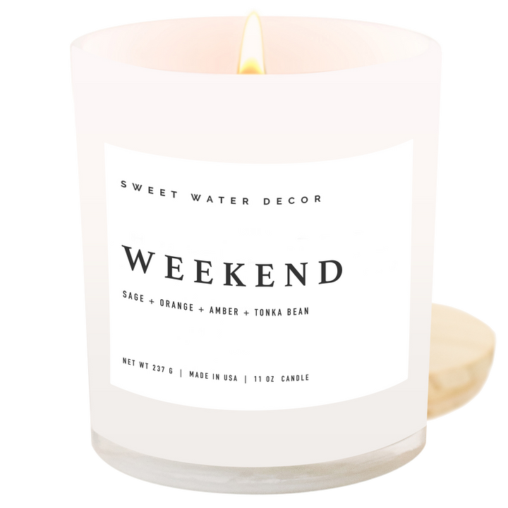 Lit candle in a white opaque jar with wooden lid and black text on a white label.