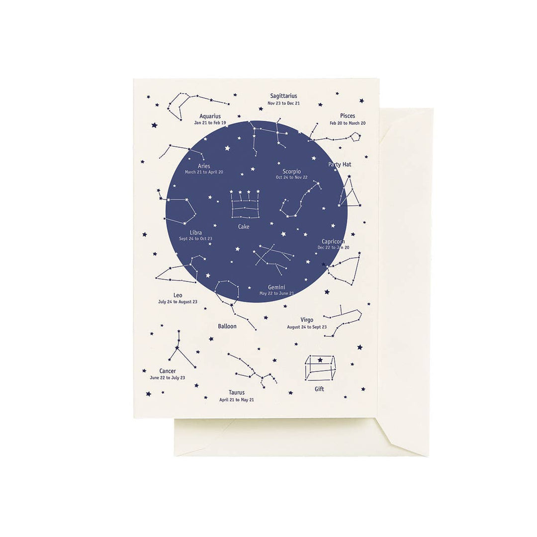 An off-white greeting card featuring a navy blue celestial design with constellations and stars.