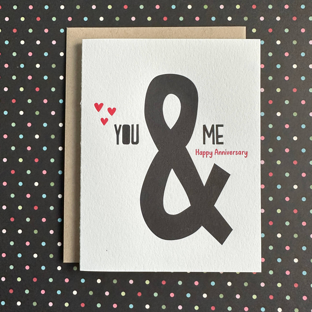 Large ampersand, with smaller black text on either side, on white cardstock. Three red hearts on the left.