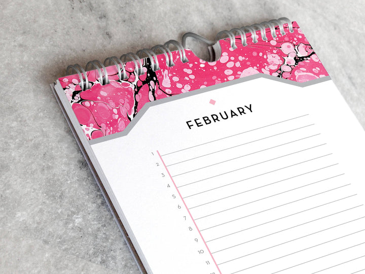 Page for February with marbled paper in shades of pink at the top and bottom. Below the month title is a line for each day of the month.