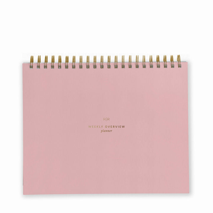 Cover of weekly planner in dusty rose with gold spiral binding at top.
