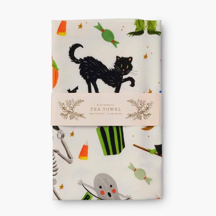 Folded towel in packaging band, showing black cat, ghost and other Halloween objects.