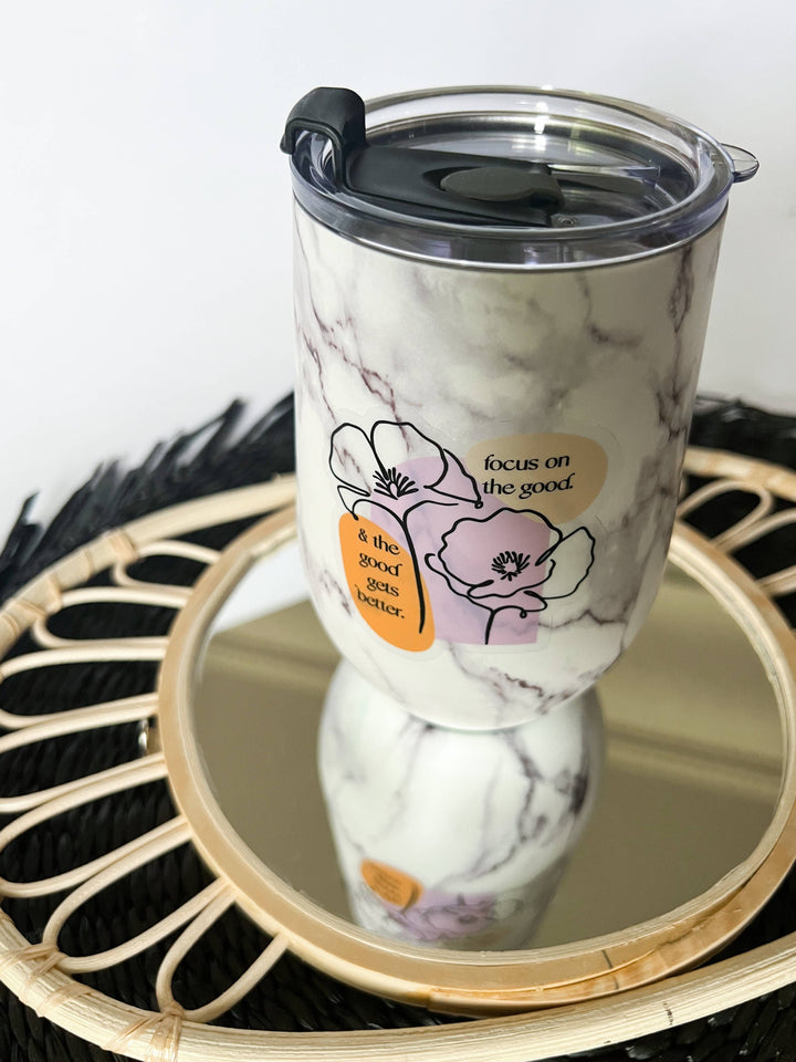 Sticker on a marble-patterned insulated tumbler with a clear lid and flip spout, displayed on a round mirror tray.