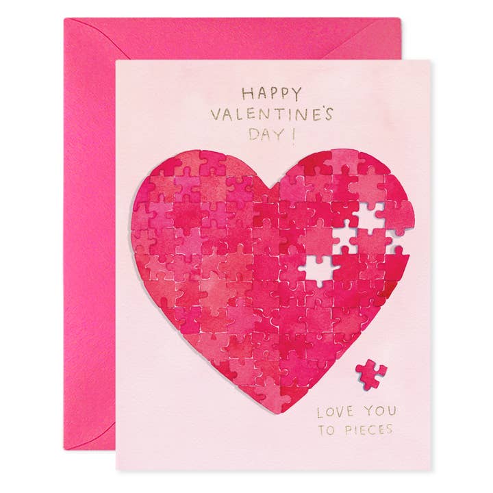 Front of card with large heart in shades of red composed of puzzle pieces, with four pieces missing and one outside the heart. Light pink background and red envelope.