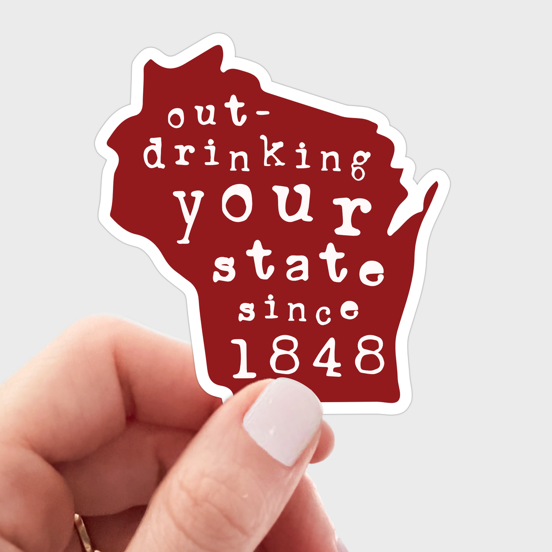 Red sticker in the shape of the state of Wisconsin with hand lettering in white.