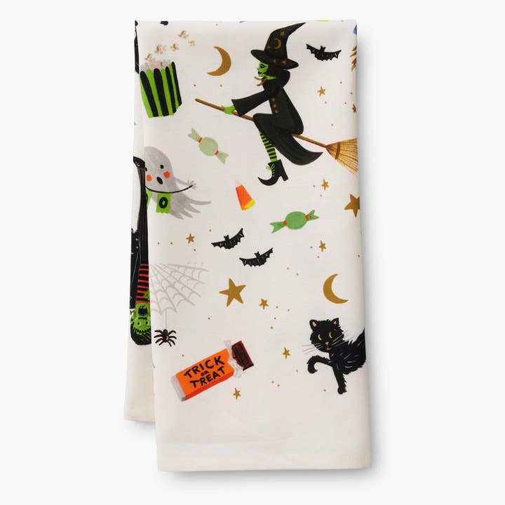 Folded towel showing wtich on broom, bats, black cat, ghost and other Halloween objects.