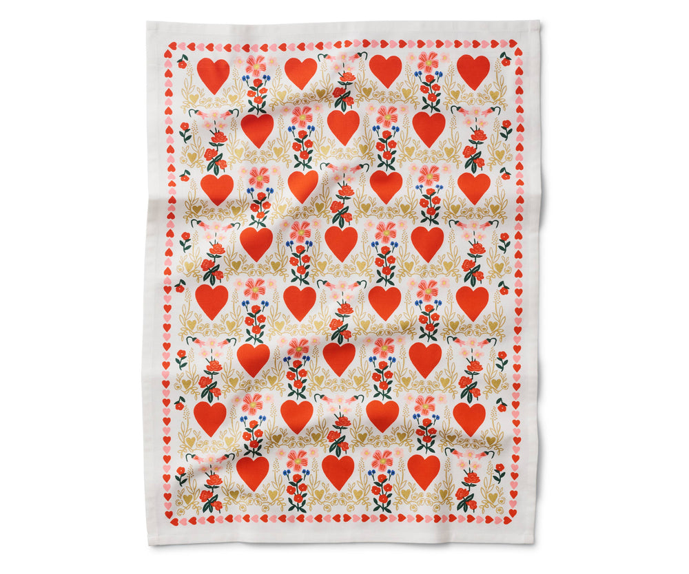 Open tea towel with a pattern of red hearts in a light gold flowery border and small bouquets of red flowers, and a border of small red and pink hearts.