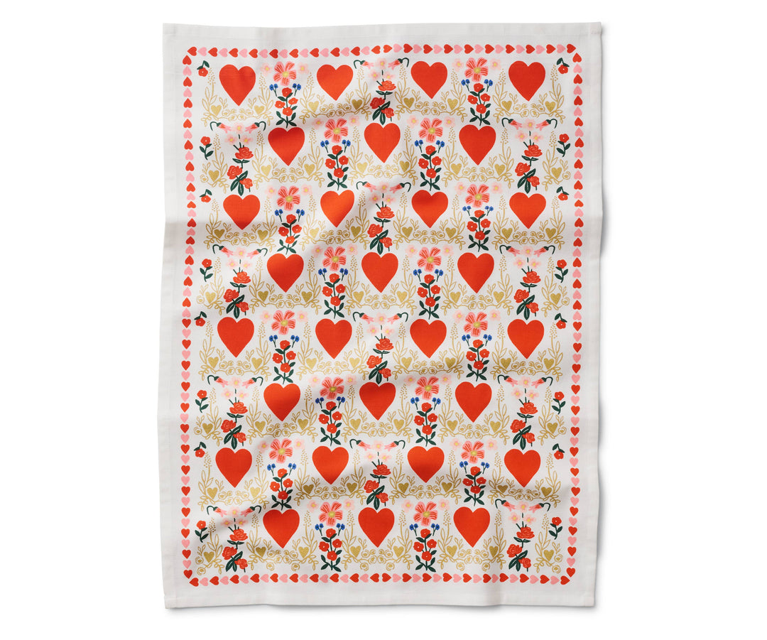 Open tea towel with a pattern of red hearts in a light gold flowery border and small bouquets of red flowers, and a border of small red and pink hearts.