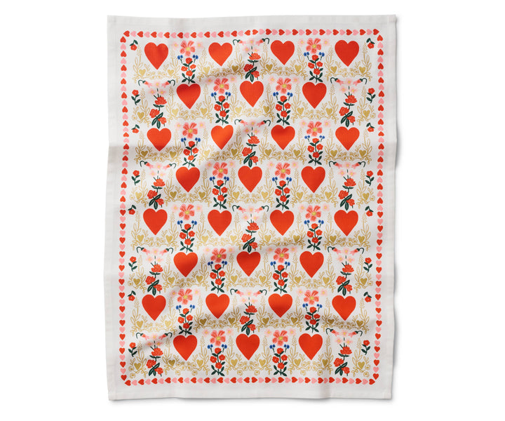 Open tea towel with a pattern of red hearts in a light gold flowery border and small bouquets of red flowers, and a border of small red and pink hearts.