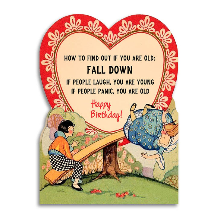 Vintage-style birthday card with two girls on a seesaw, one in the process of falling off, below a heart-shape containing the text. 