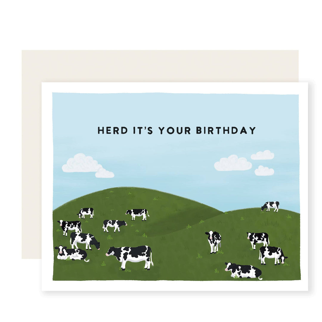 Cows on hills under a blue sky with clouds. Black text in block letters in the sky.