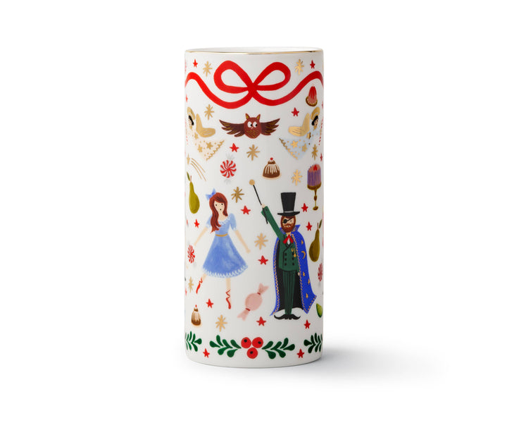 Cylindrical vase with Nutcracker illustrations, a red ribbon at the top, and holly at the bottom, on an off-white background.