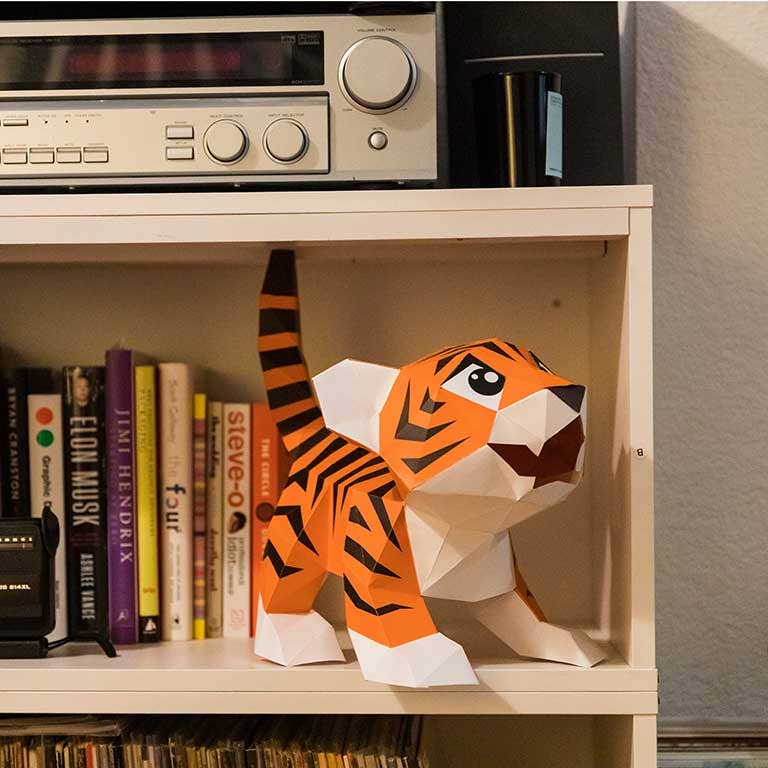 Completed 3D paperboard tiger cub, shown in a bookcase. 