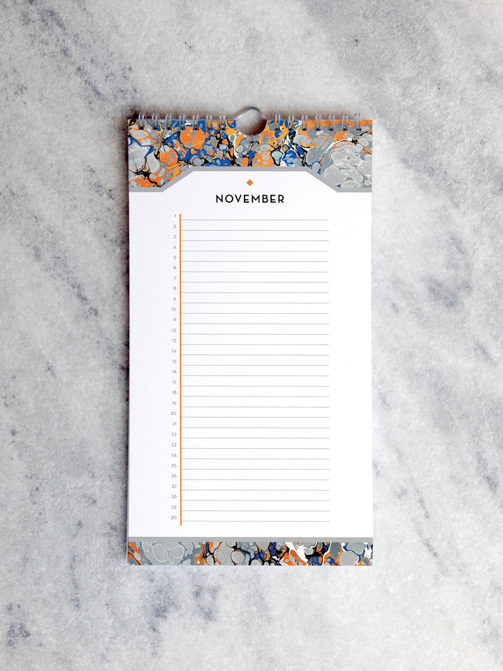 Page for November with marbled paper in shades of orange, blue and gray at the top and bottom. Below the month title is a line for each day of the month.