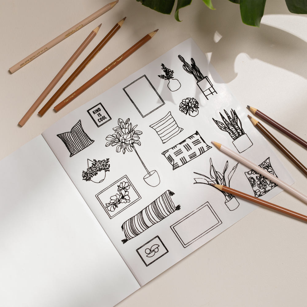 Book opened to show black line art illustrations of items found in a house, surrounded by pencils.