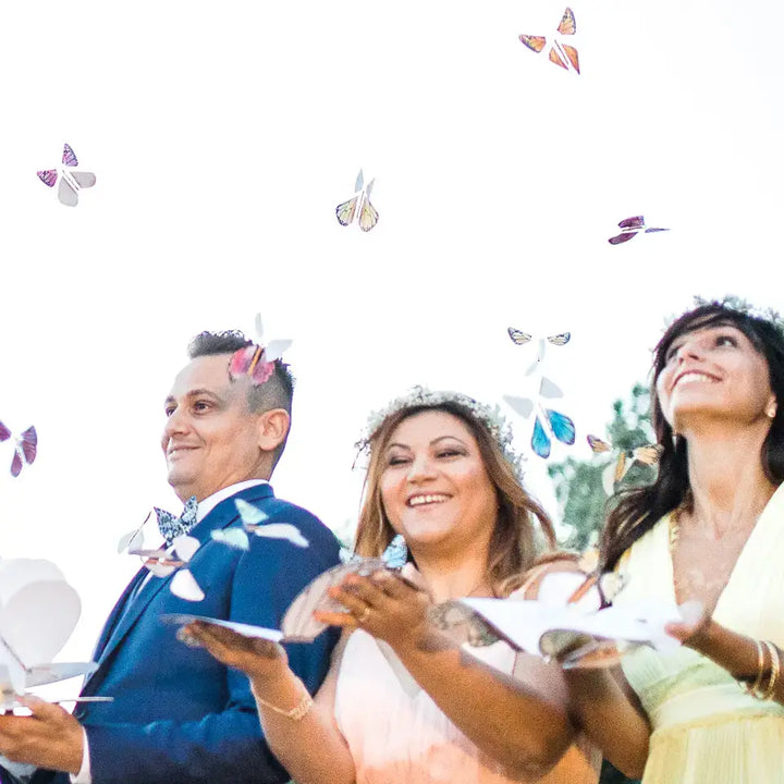 Three people at a celebration holding open cards with butterflies flying above them.
