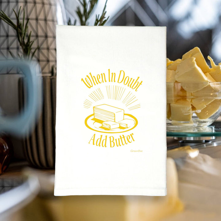 Yellow text, in serif font, and an image of a stick of butter on a plate with two slices cut, on a white towel superimposed on a photo of a bowl with pats of butter.