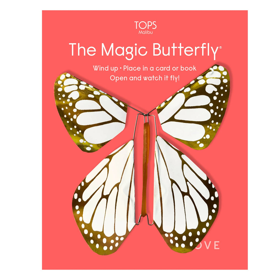 Butterfly-shaped wind-up object with gold and white wings on a red card.