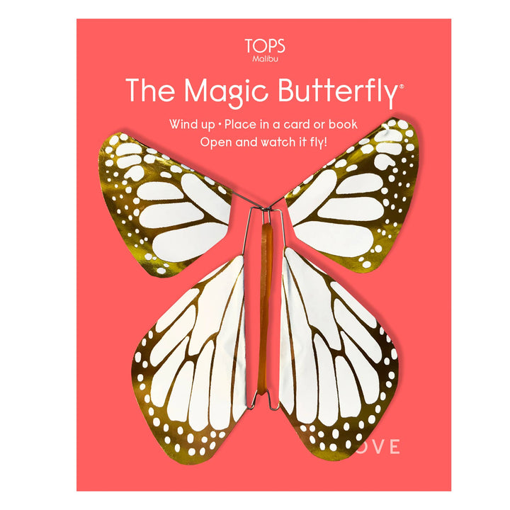 Butterfly-shaped wind-up object with gold and white wings on a red card.