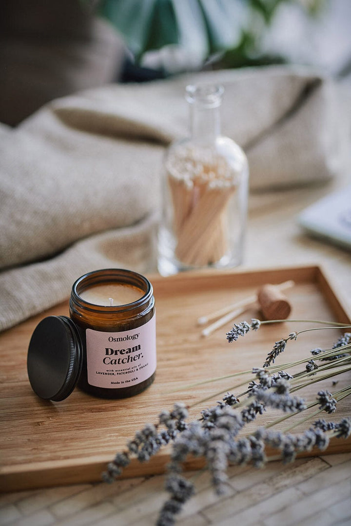 Open brown glass jar with lid on a tree with lavender sprigs, a cork and some candles