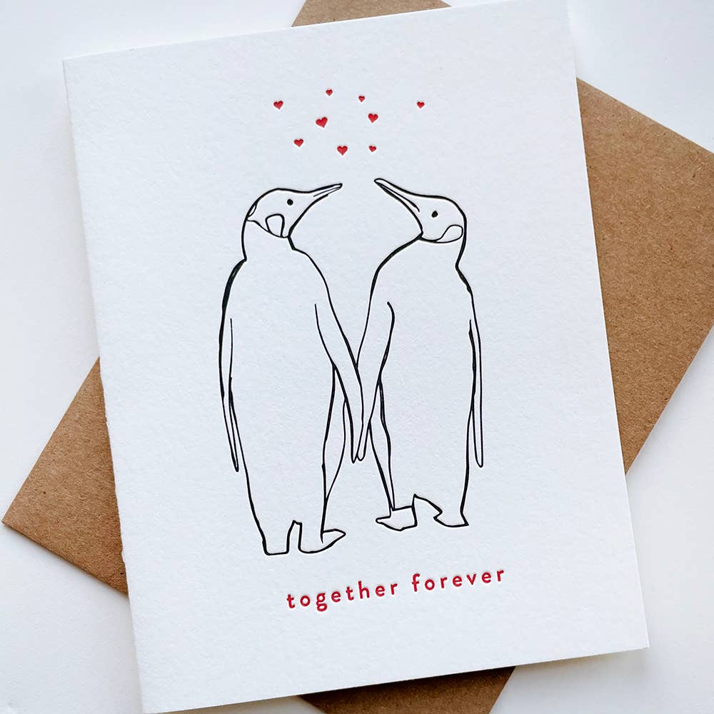 Two hand drawn penguins in black, holding "hands," with red hearts above and text below.