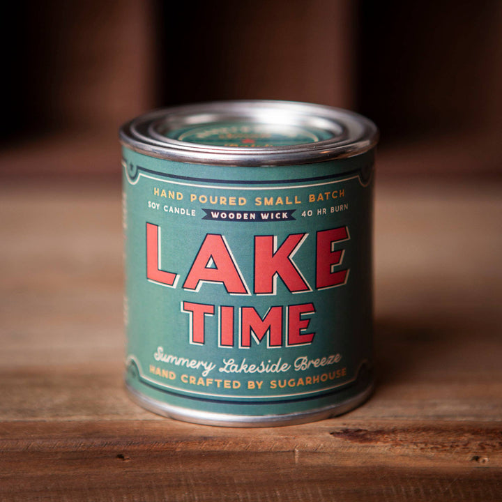 Soy candle in tin. Aqua label with red-orange lettering. Label is Lake Time Summery Lakeside Breeze.