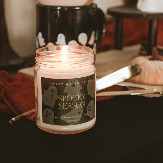 Scented soy candle in clear glass jar with a decorative label and metal lid. Label is Spooky Season  Wood / Warm Spice / Citrus