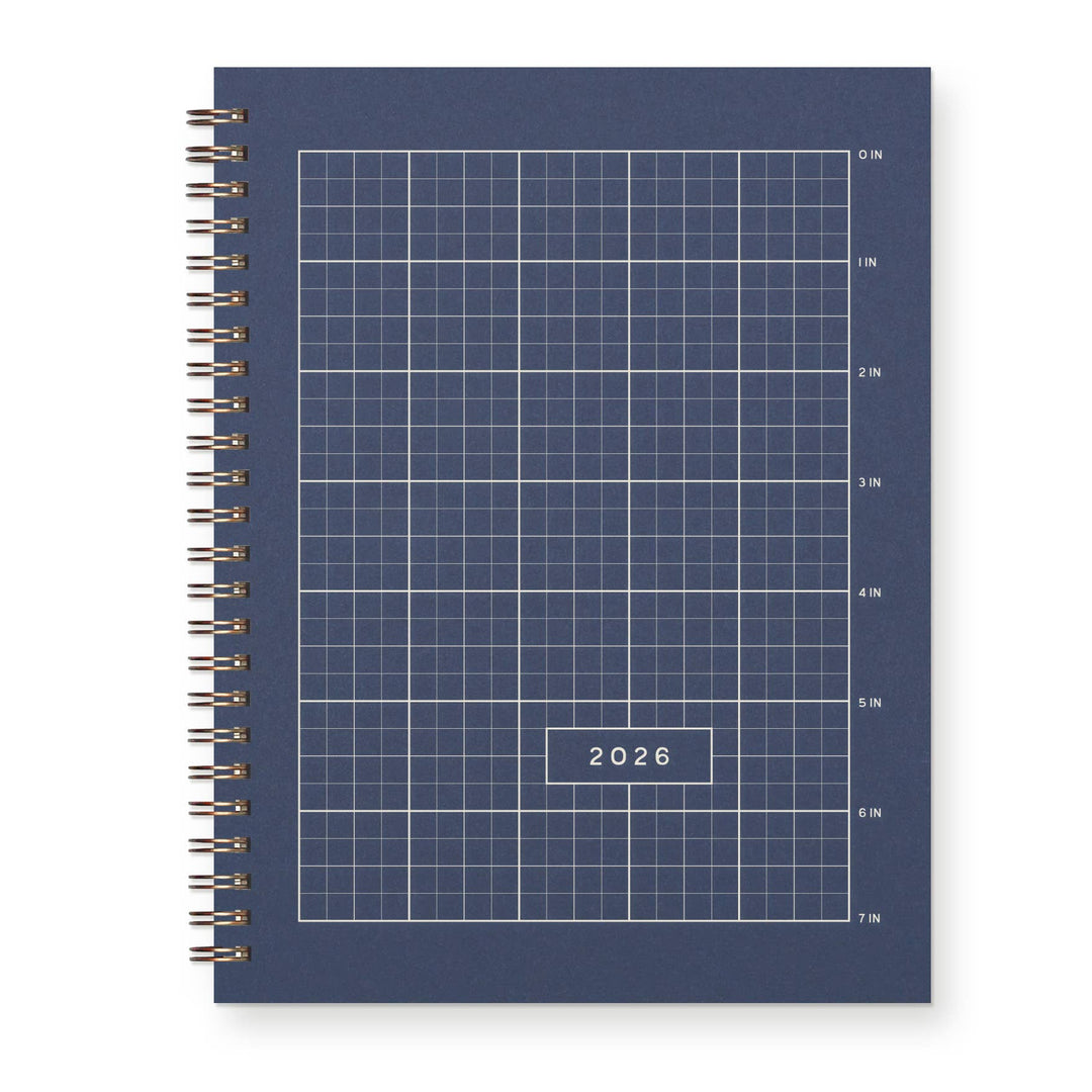 Cover of a deep blue spiral-bound planner with grid design and labeled '2026' with spiral Wire-O binding.