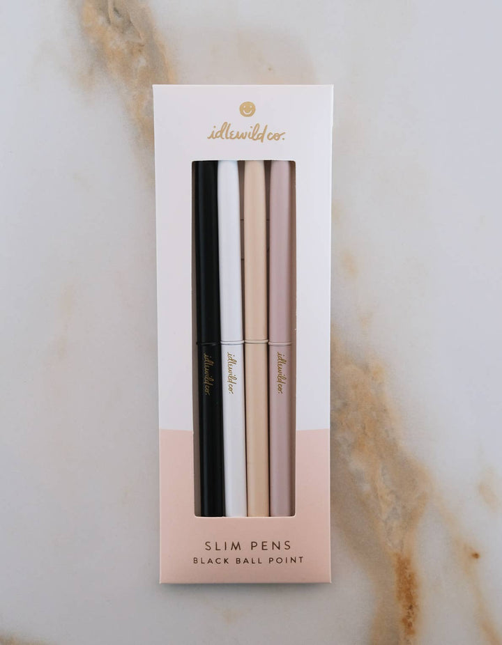 Set of four slim pens in black, white, blush, and beige in a white and blush box. 