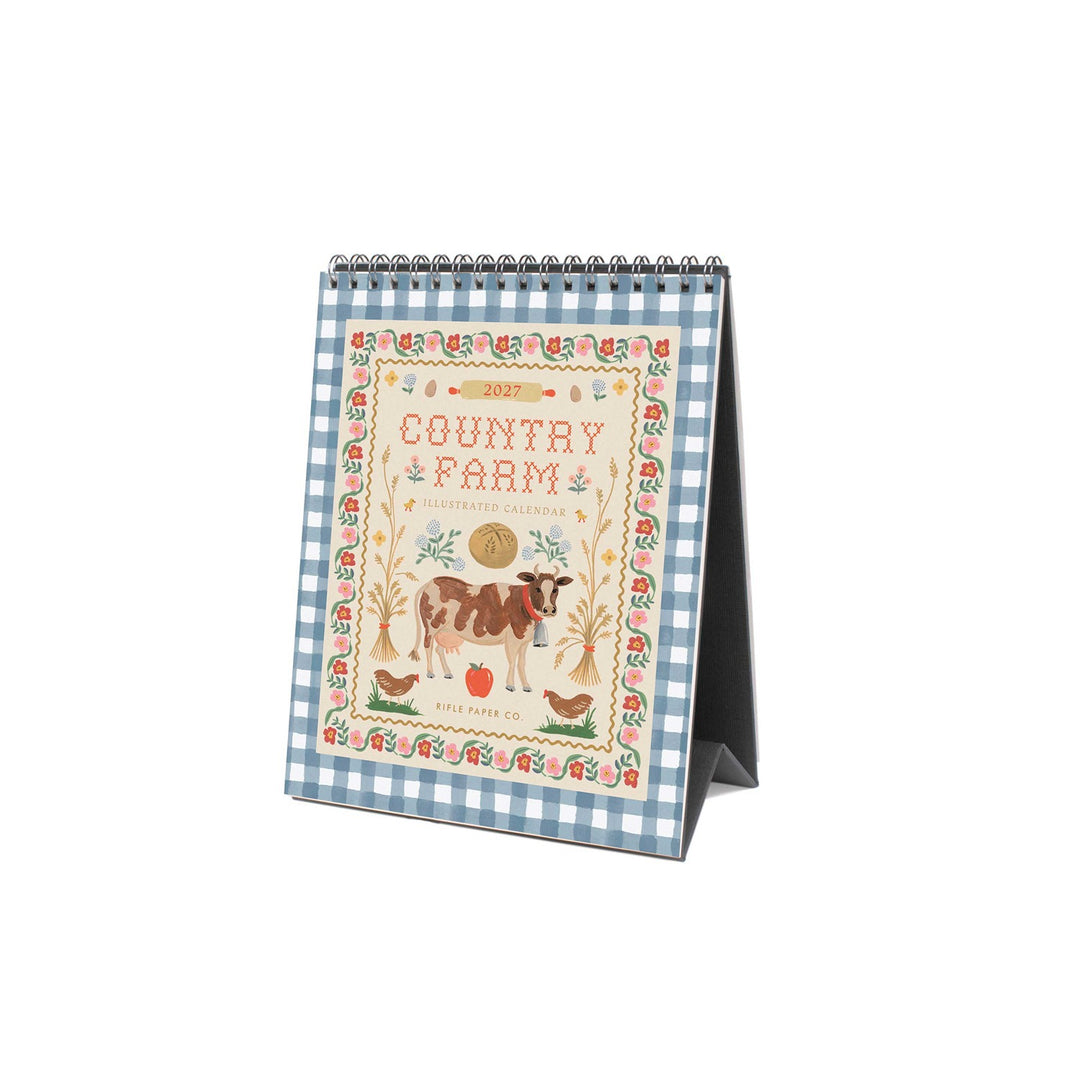 Cover of calendar, open to stand on a desk, with a cow and other farm images, and a checked border.
